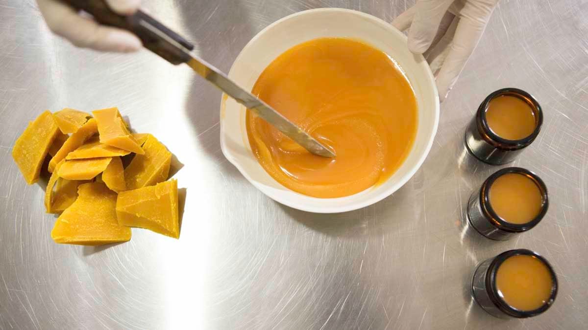 Person making CBD cream for pain inside a lab wearing white gloves